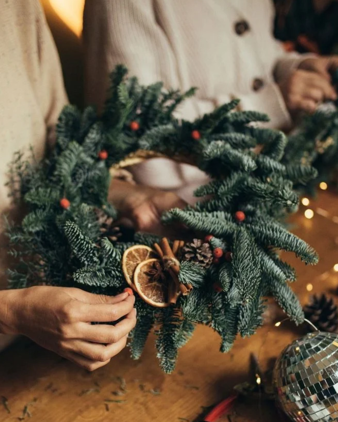 Mains décorant une couronne de Noël en sapin